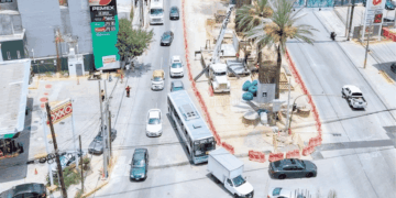 Aerial View of a Busy Street Under Construction with a Circular Median Containing a Palm Tree and Construction Equipment, and Cars Around It. - Glen Facturero