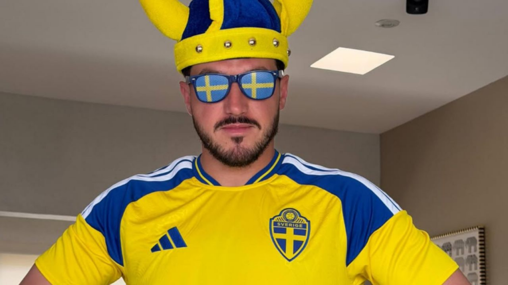 Image - Glen Facturero Samuel García Wearing a Sweden National Team Jersey in Yellow and Blue, with Blue Sunglasses Showing the Swedish Flag and a Yellow Crown Hat. - Glen Facturero