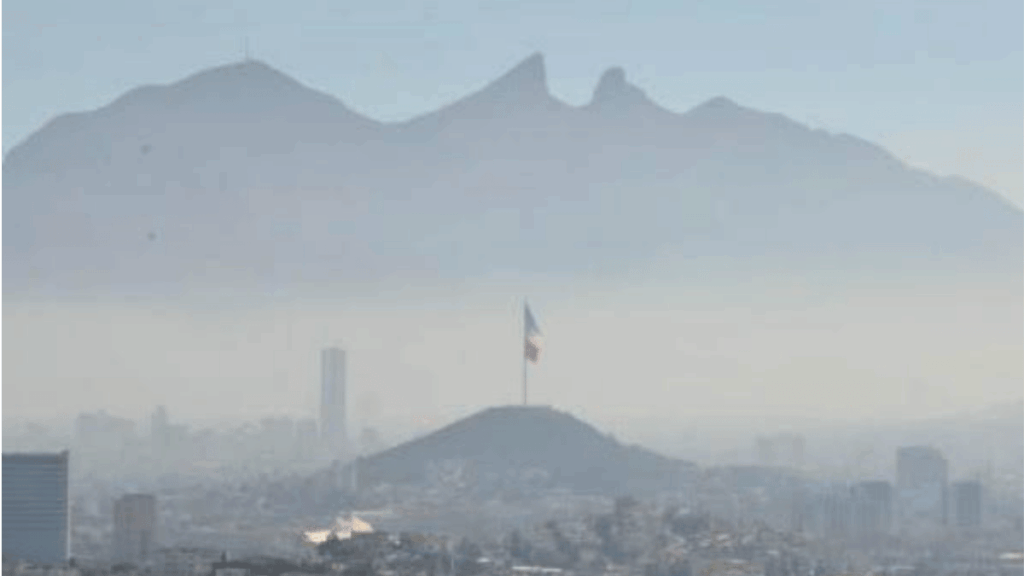 Flag Atop a Hill Overlooking a Hazy City Skyline with Distant Mountains in the Background, Under a Pale Blue Sky. - Glen Facturero