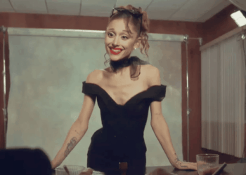 Woman in an Off-shoulder Black Dress with Red Lipstick and Sunglasses on Her Head, Smiling Behind a Table in a Photography Studio. - Glen Facturero