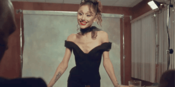 Woman in an Off-shoulder Black Dress with Red Lipstick and Sunglasses on Her Head, Smiling Behind a Table in a Photography Studio. - Glen Facturero