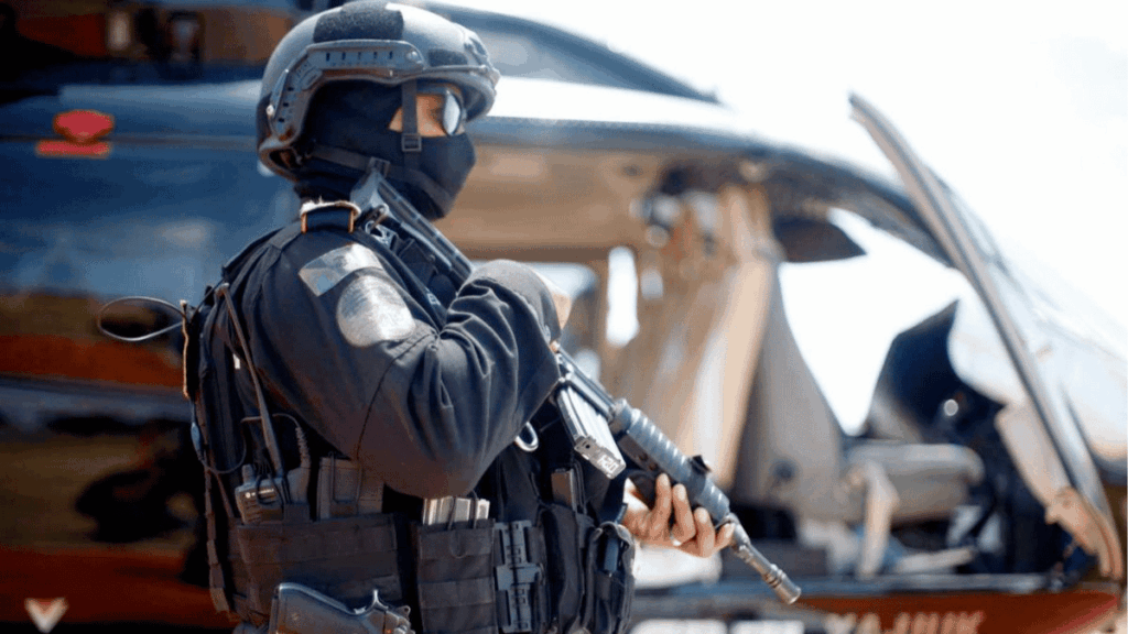 Tactical Police or Military Operator in Full Gear with Helmet, Standing Beside an Open Helicopter and Holding a Rifle - Glen Facturero