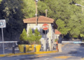 Small Security Booth at a Gated Entrance with a Red 'alto' Stop Sign, Barrier Gate, and Yellow Planters Nearby. - Glen Facturero